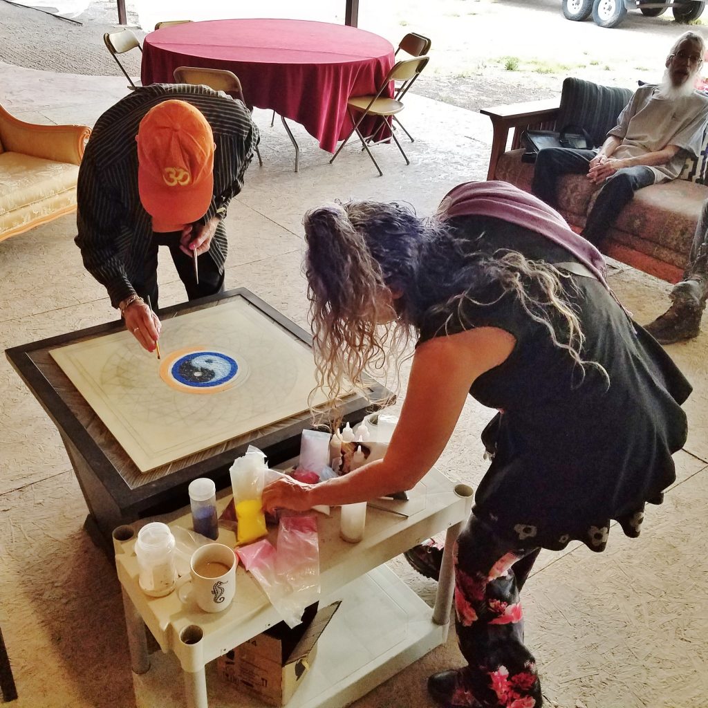 Two people painting a picture on top of a table.