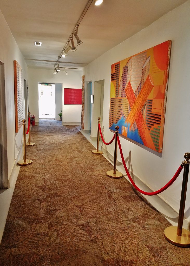 A long hallway with red rope and art on the wall.